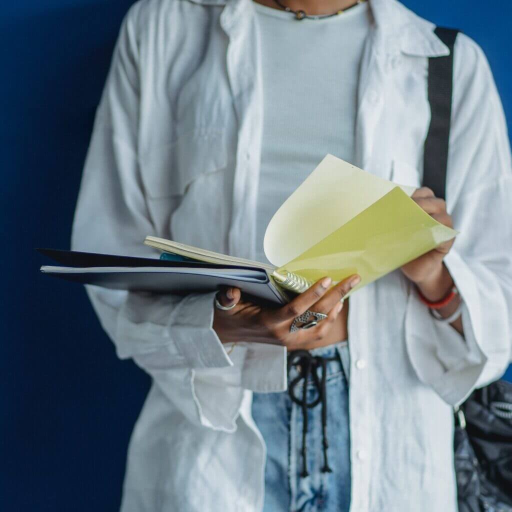 Un cahier dans la main d'un étudiant présentant l'aide à la préparation aux examens proposé par le centre d'animation itinérant le bazar culturel