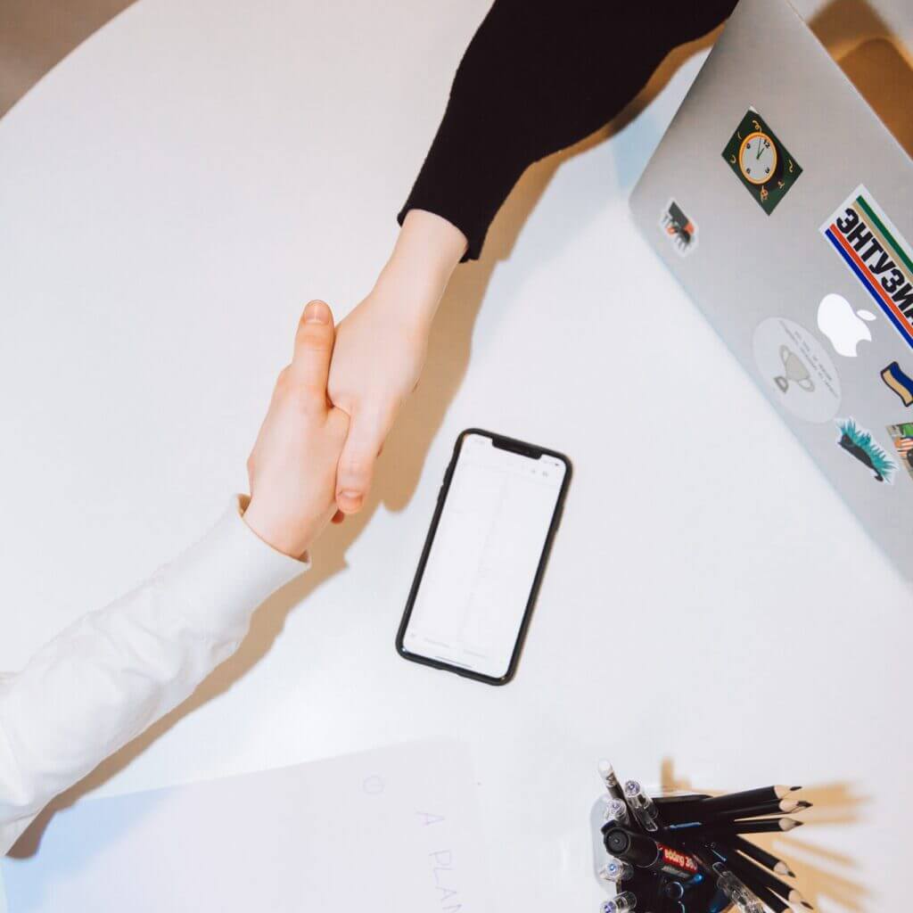 Une poignée de mains échangées au dessus d'un bureau présentant le bilan de compétences proposé par le centre d'animation itinérant le bazar culturel