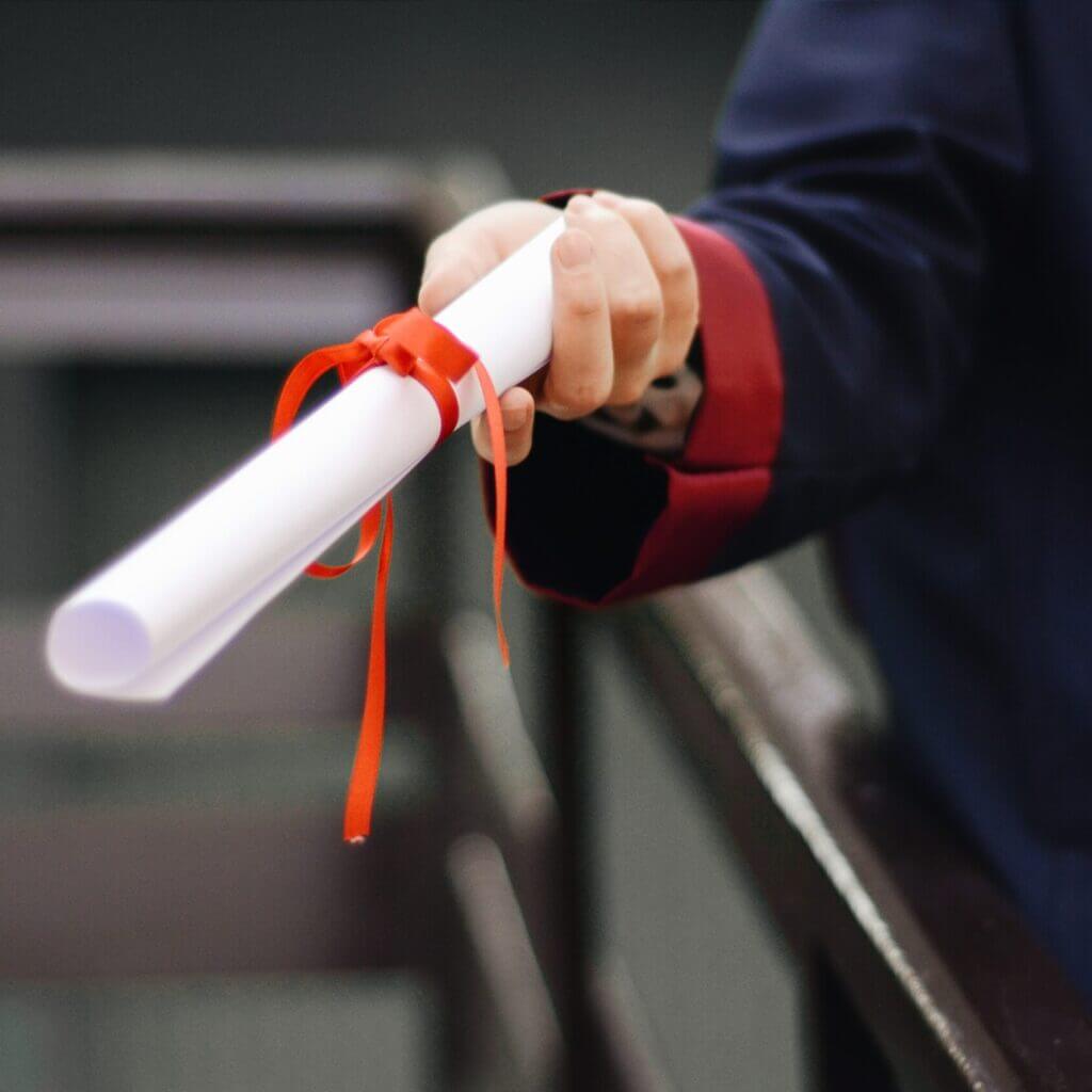 Un diplôme tenu dans la main d'un étudiant pour illustrer la prestation de coaching scolaire proposé par le centre d'animation itinérant le bazar culturel